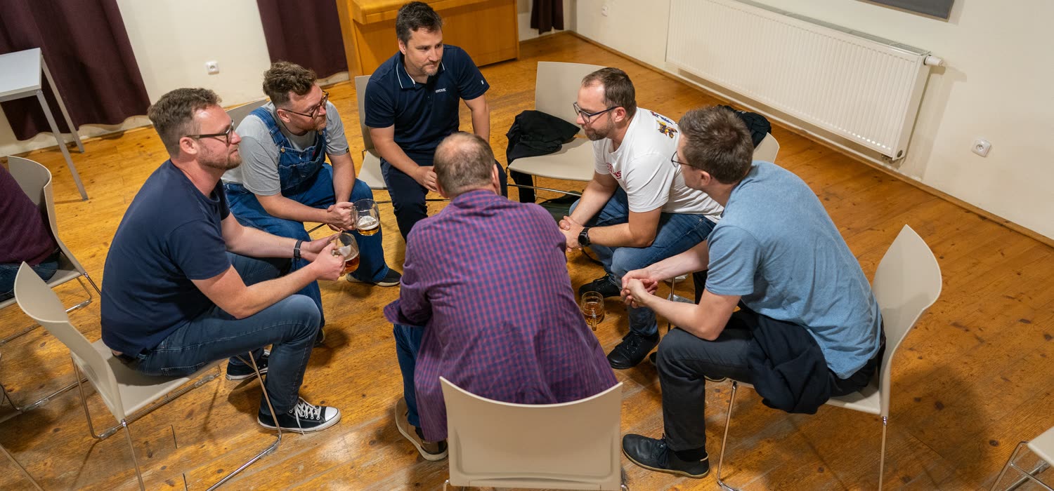 Šest účastníků sedí v kruhu a živě spolu diskutuje.