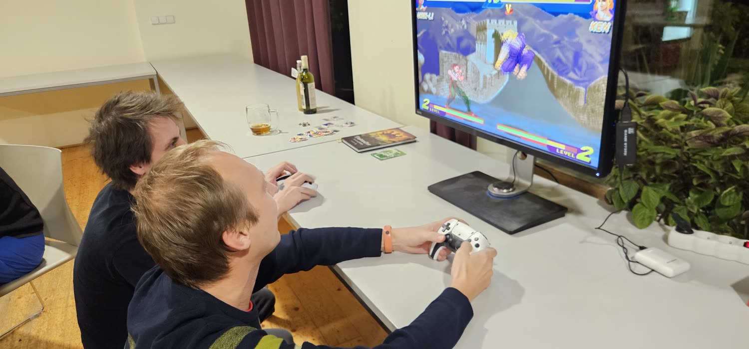 Dva účastníci hrají proti sobě bojovou hru na monitoru.